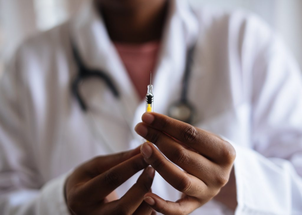 doctor holding miniature syringe